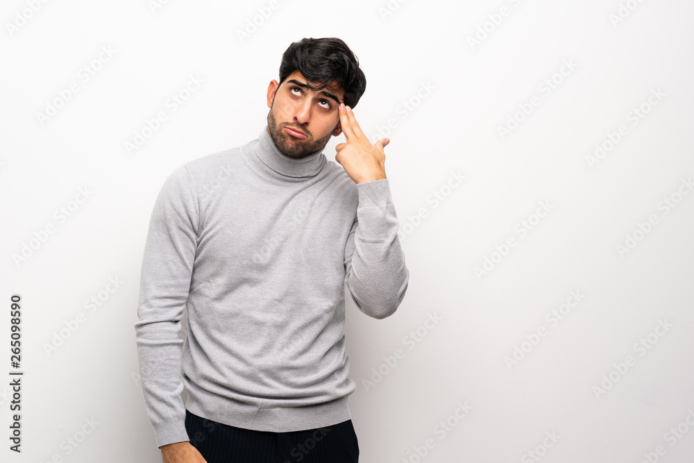 Young man over isolated white wall with problems making suicide gesture Young man over isolated white wall with problems making suicide gesture