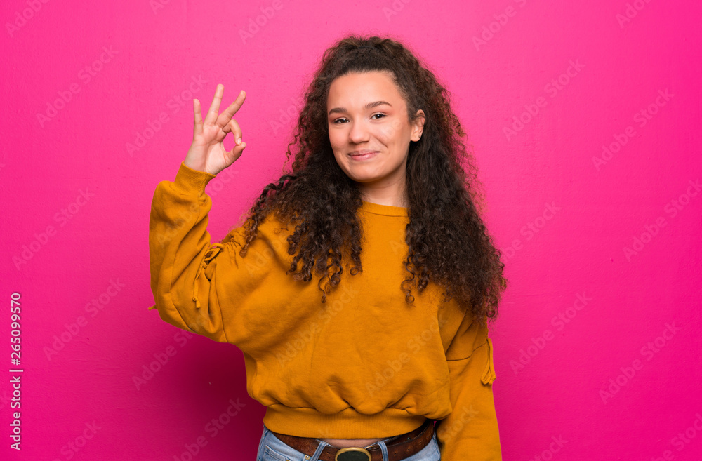 Teenager girl over pink wall showing ok sign with fingers Teenager girl over pink wall showing ok sign with fingers