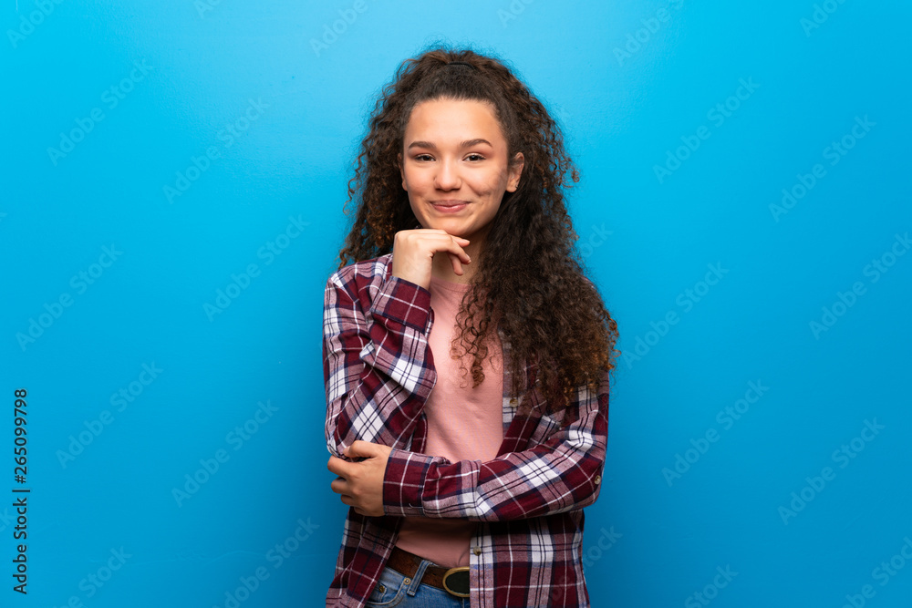 Teenager girl over blue wall smiling and looking to the front with confident face Teenager girl over blue wall smiling and looking to the front with confident face
