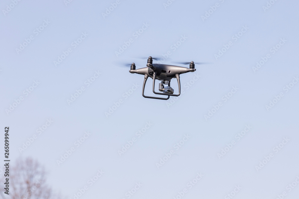 Landing a droned hand with spinning propellers. Flying drone on blue sky. Landing a droned hand with spinning propellers. Flying drone on blue sky.