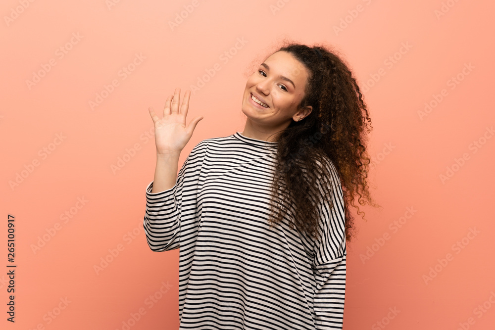Teenager girl over pink wall saluting with hand with happy expression Teenager girl over pink wall saluting with hand with happy expression
