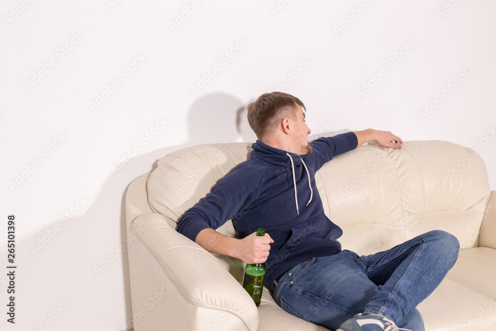 Depression and alcoholism concept - Aggressive male alcoholic sitting on the sofa Depression and alcoholism concept - Aggressive male alcoholic sitting on the sofa