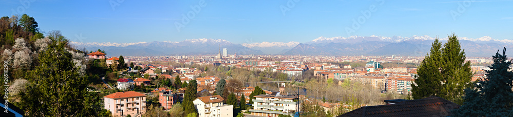 Aerial panoramic view on Turin city center with Mole Antonelliana, modern skyscraper and other buildings, clear blue sky morning with Alps on background