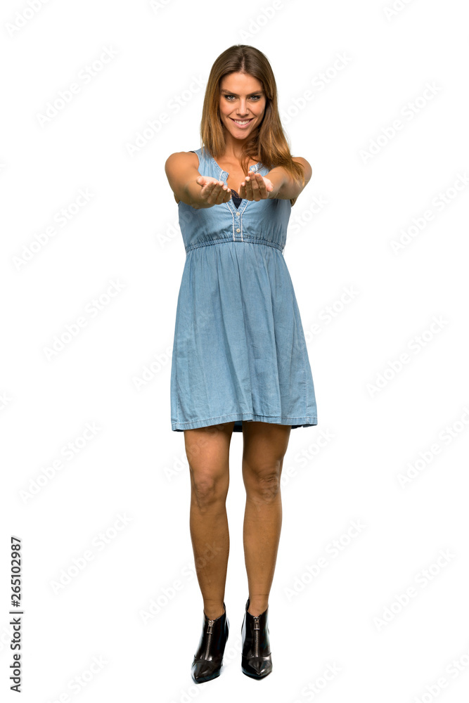 A full-length shot of a Blonde woman with jean dress holding copyspace imaginary on the palm to insert an ad over isolated white background A full-length shot of a Blonde woman with jean dress holding copyspace imaginary on the palm to insert an ad over isolated white background