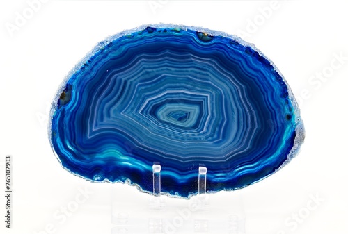 Agate is a rock consisting primarily of cryptocrystalline silica, chiefly chalcedony, alternating with microgranular quartz. Blue polished specimen slice isolated on white limbo background photo