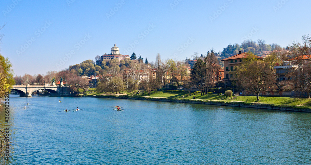 Canoe crews train on the Po river in Turin near the Umberto I bridge, with the backdrop of the Church of the Monte dei Cappuccini, in a sunny spring morning