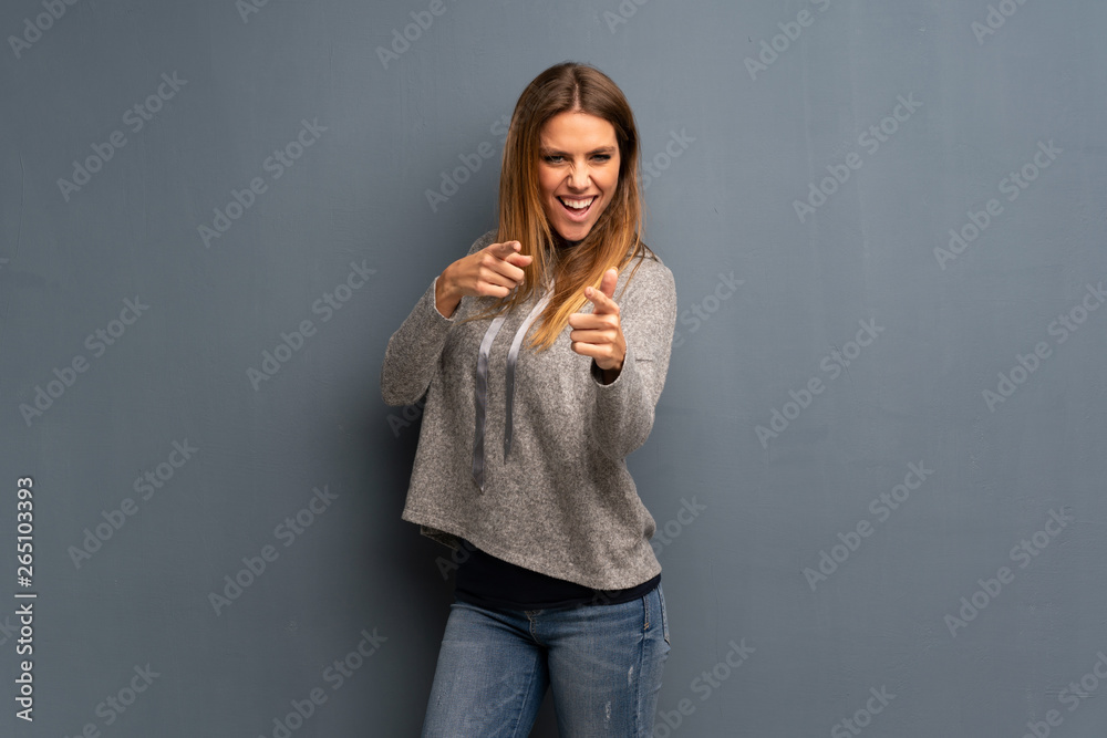 Blonde woman over grey background pointing to the front and smiling Blonde woman over grey background pointing to the front and smiling