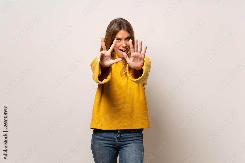 Woman with yellow sweater over isolated wall counting eight with fingers Woman with yellow sweater over isolated wall counting eight with fingers