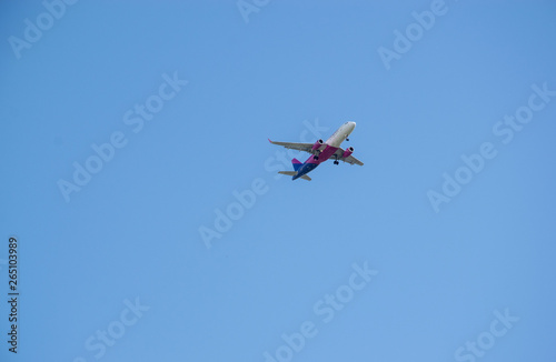 View from below of an airplane flying high in blue sky