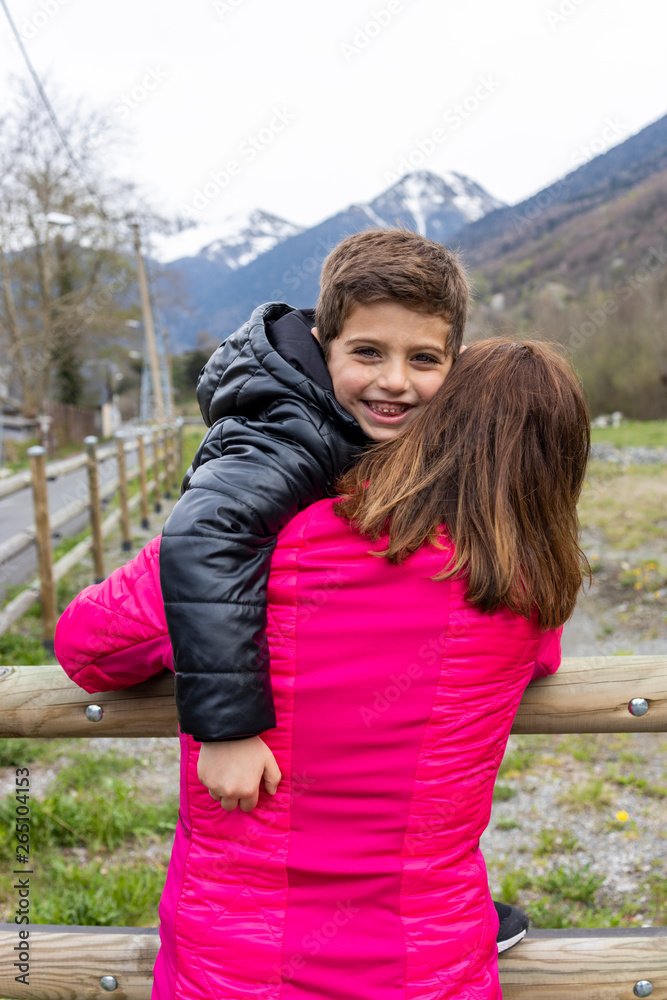 Fototapeta premium Mother and son hugging on a fence in the countryside