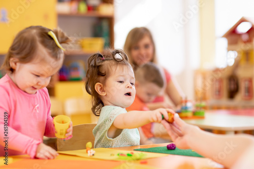 Little kid girl learning to use colorful play dough in kindergarten
