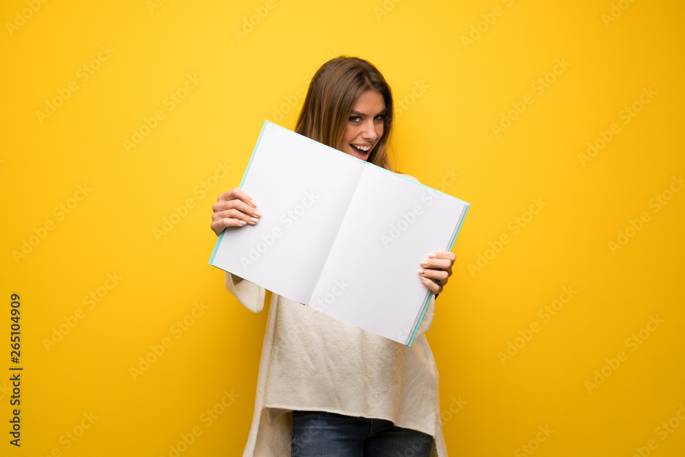 Blonde woman over yellow wall holding an empty white placard Blonde woman over yellow wall holding an empty white placard