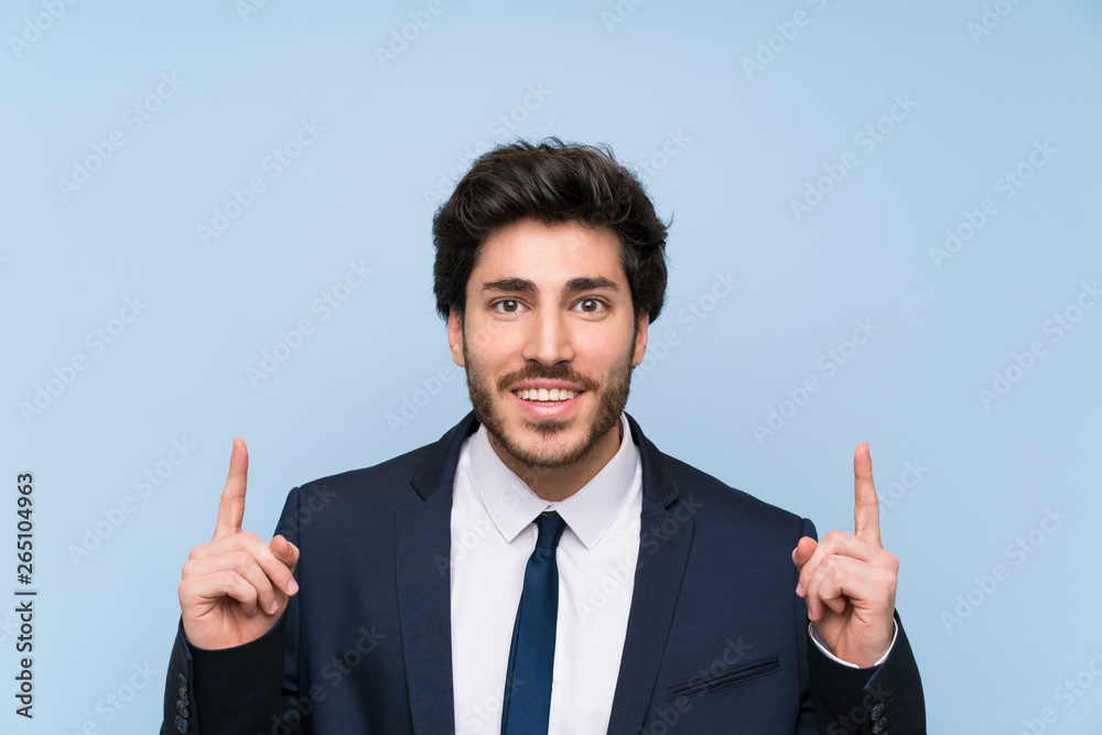 Businessman over isolated blue wall pointing up a great idea Businessman over isolated blue wall pointing up a great idea