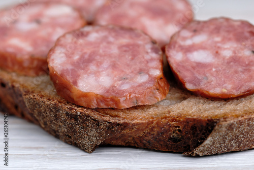 Sliced sausage on bread  opposite light background. Shallow depth of field