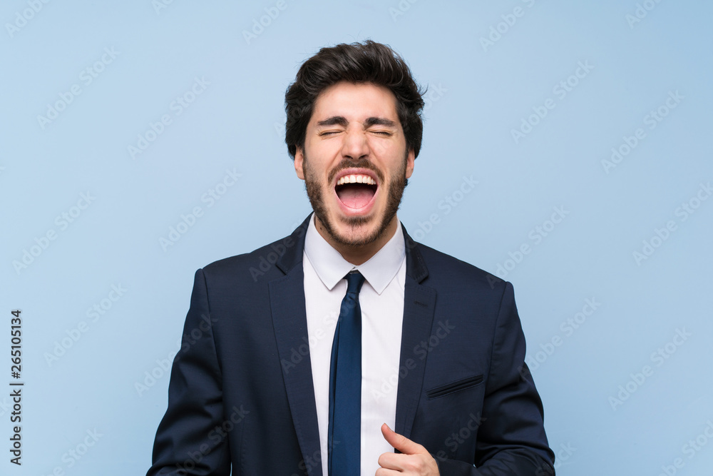 Businessman over isolated blue wall shouting to the front with mouth wide open Businessman over isolated blue wall shouting to the front with mouth wide open