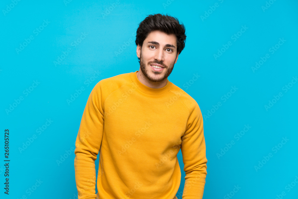 Handsome over isolated blue wall laughing