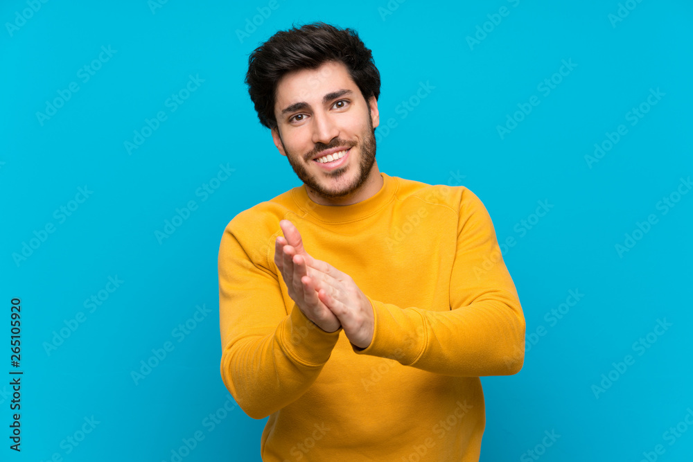 Handsome over isolated blue wall applauding after presentation in a conference Handsome over isolated blue wall applauding after presentation in a conference