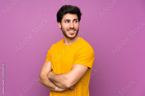 Handsome over isolated purple wall with arms crossed and happy
