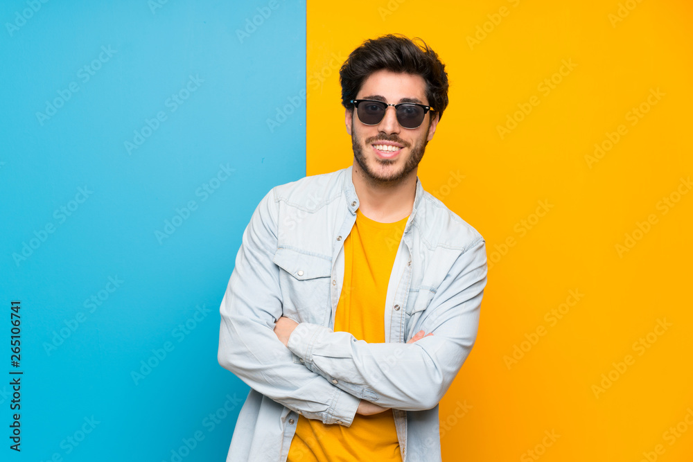 Handsome over isolated colorful background with glasses and happy
