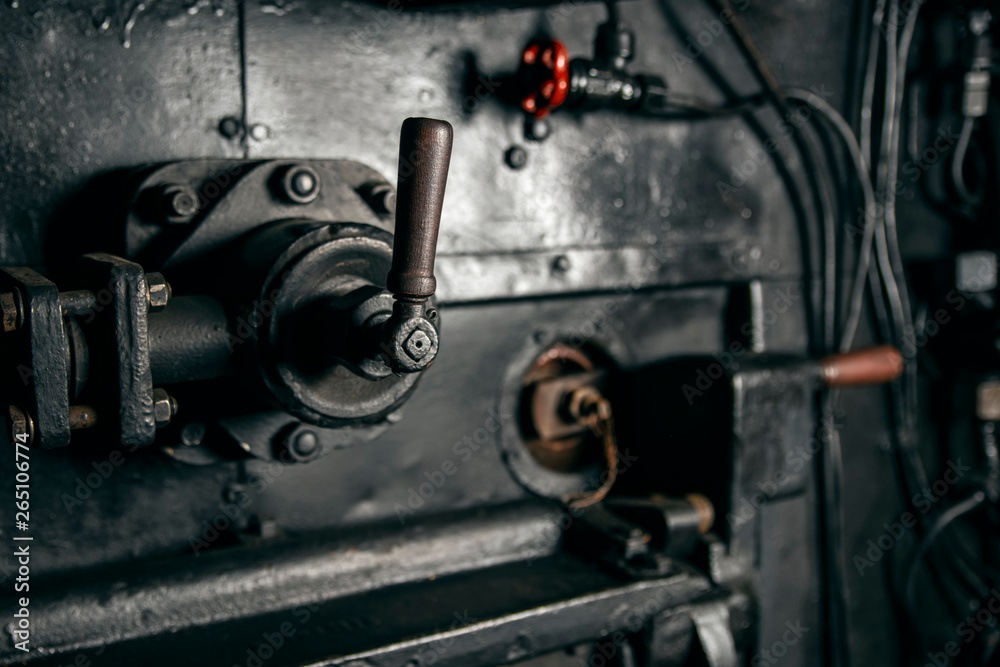 Metal lever mechanism with a wooden handle in the cabin of the locomotive, industrial background.