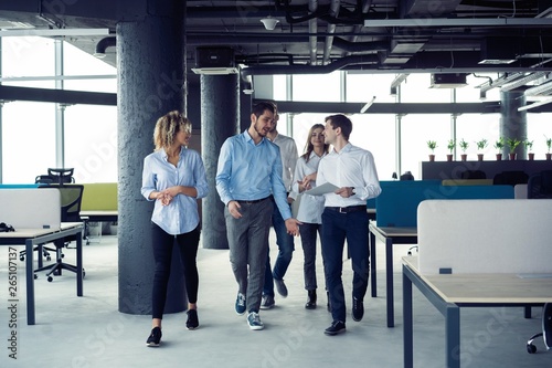 Taking their business on the move. Full length of young modern people in smart casual wear having a discussion while walking through the large modern office.