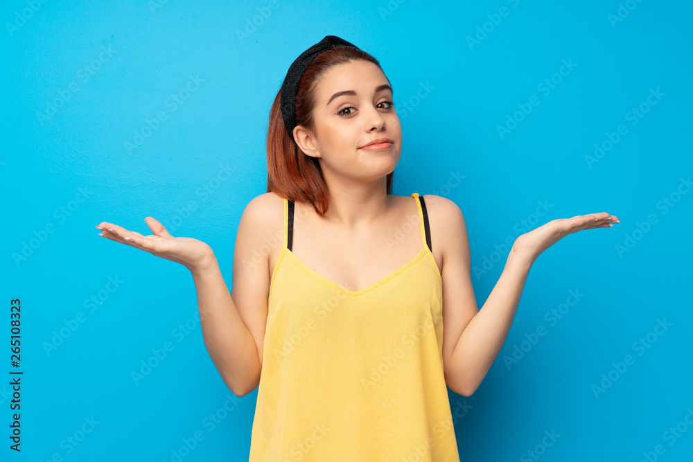 Young redhead woman over blue background making doubts gesture Young redhead woman over blue background making doubts gesture