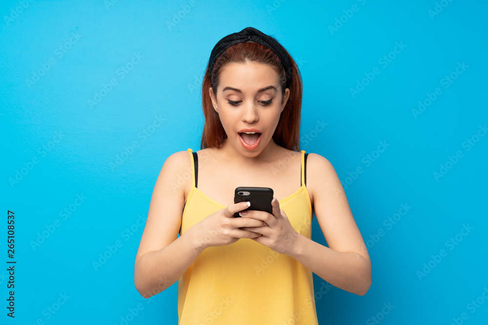 Young redhead woman over blue background surprised and sending a message Young redhead woman over blue background surprised and sending a message