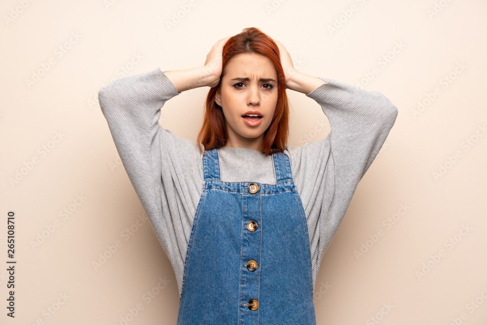 Young redhead woman over isolated background takes hands on head because has migraine Young redhead woman over isolated background takes hands on head because has migraine