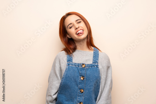 Young redhead woman over isolated background showing tongue at the camera having funny look