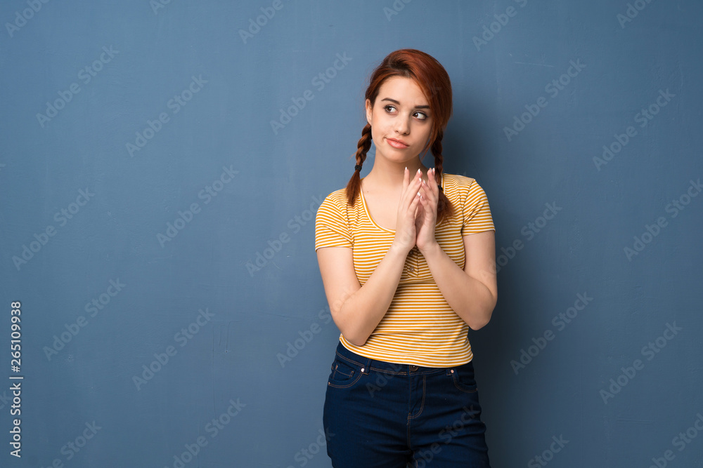 Young redhead woman over blue background scheming something Young redhead woman over blue background scheming something