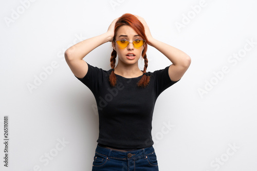 Young redhead woman over white wall frustrated and takes hands on head