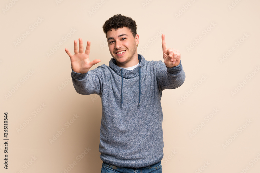 Young man over isolated wall counting six with fingers Young man over isolated wall counting six with fingers
