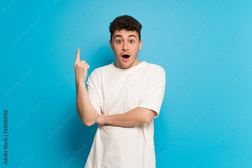 Young man over blue background thinking an idea pointing the finger up Young man over blue background thinking an idea pointing the finger up