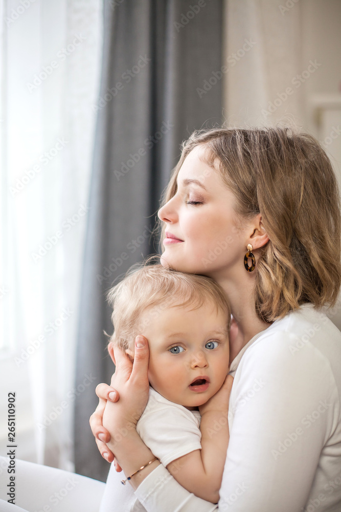 Beautiful mother and little son 9 months in the home interior. Cozy. Baby. Motherhood.