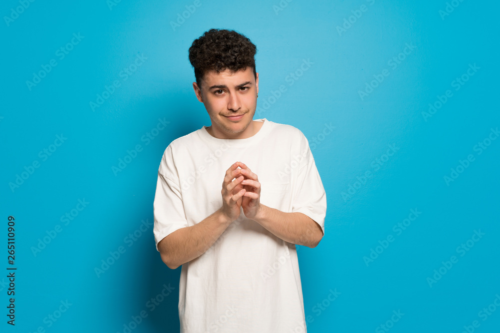 Young man over blue background scheming something Young man over blue background scheming something