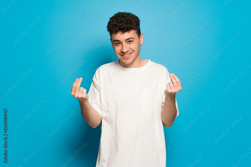 Young man over blue background making money gesture Young man over blue background making money gesture