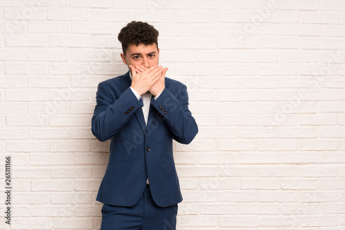 Man in suit and bow tie covering mouth with hands