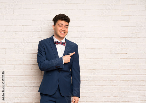 Man in suit and bow tie pointing to the side to present a product