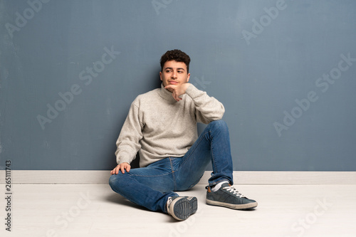 Young man sitting on the floor thinking