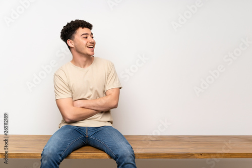 Young man sitting on table happy and smiling