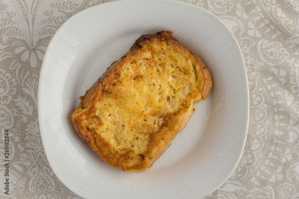 Savoury French toast slice in a white plate on patterned table