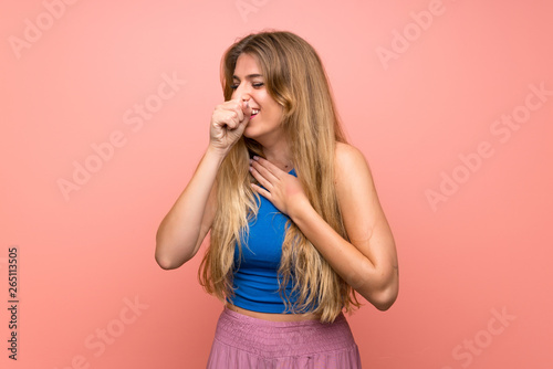 Young blonde woman over isolated pink background is suffering with cough and feeling bad