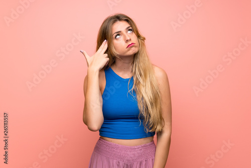Young blonde woman over isolated pink background with problems making suicide gesture