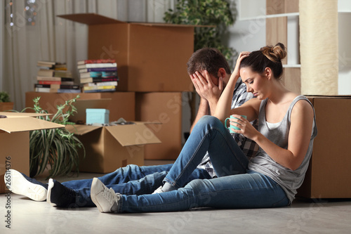 Sad evicted couple moving home complaining on the floor photo