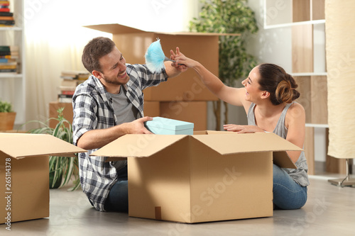 Happy couple joking moving home boxing belongings