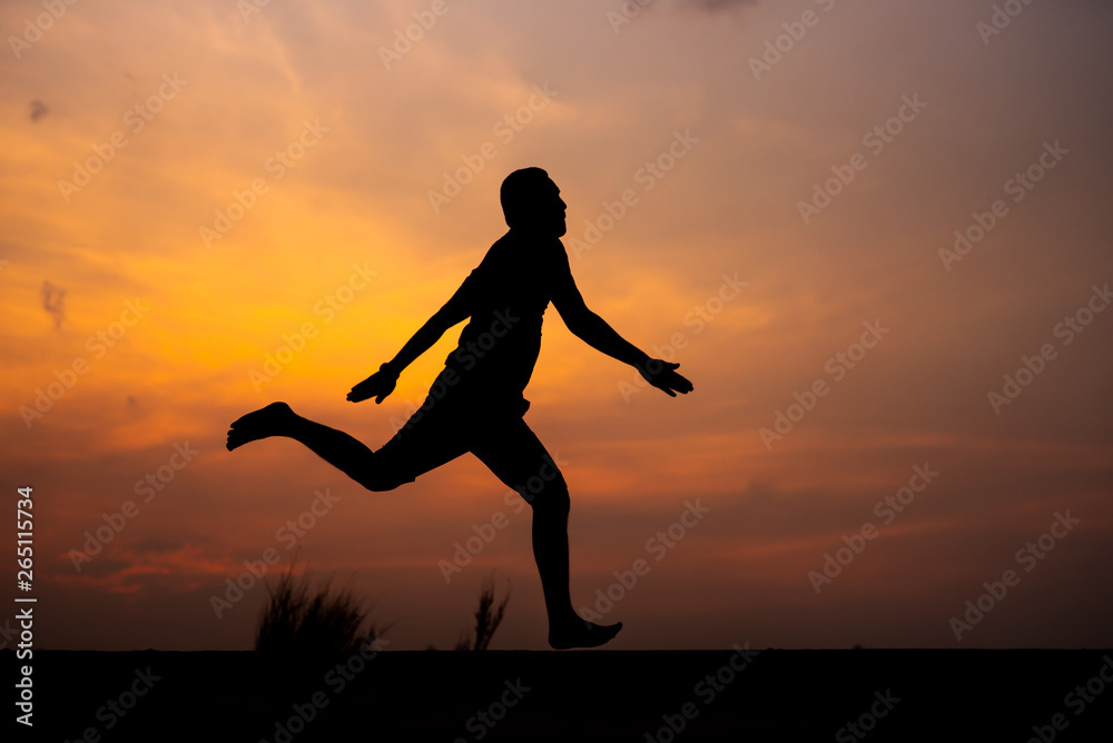 Man running alone at beautiful sunset in the road at park . Summer sport and freedom concept. Athlete training on dusk. - Image