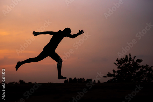 Man running alone at beautiful sunset in the road at park . Summer sport and freedom concept. Athlete training on dusk. - Image