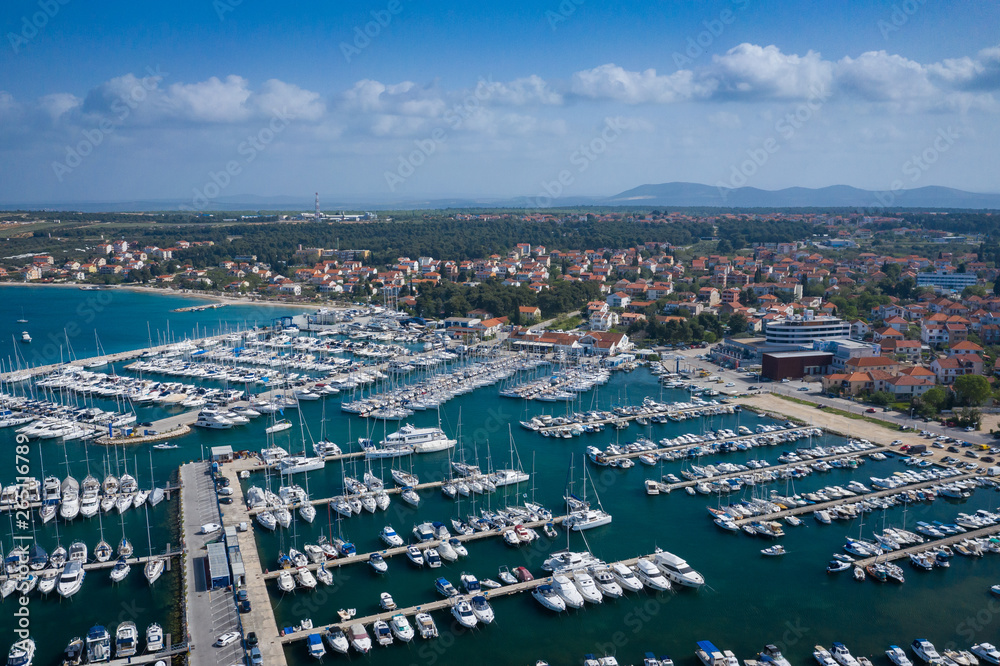 Aerial View of Yacht Club and Marina in Biograd na Moru. Summer time in Dalmatia region of Croatia. Coastline and turquoise water and blue sky. Photo made by drone from above.