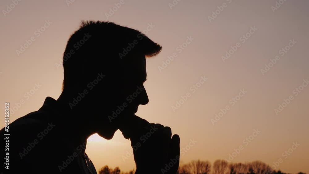 Profile of a man eating an appetizing burger at sunset Profile of a man eating an appetizing burger at sunset
