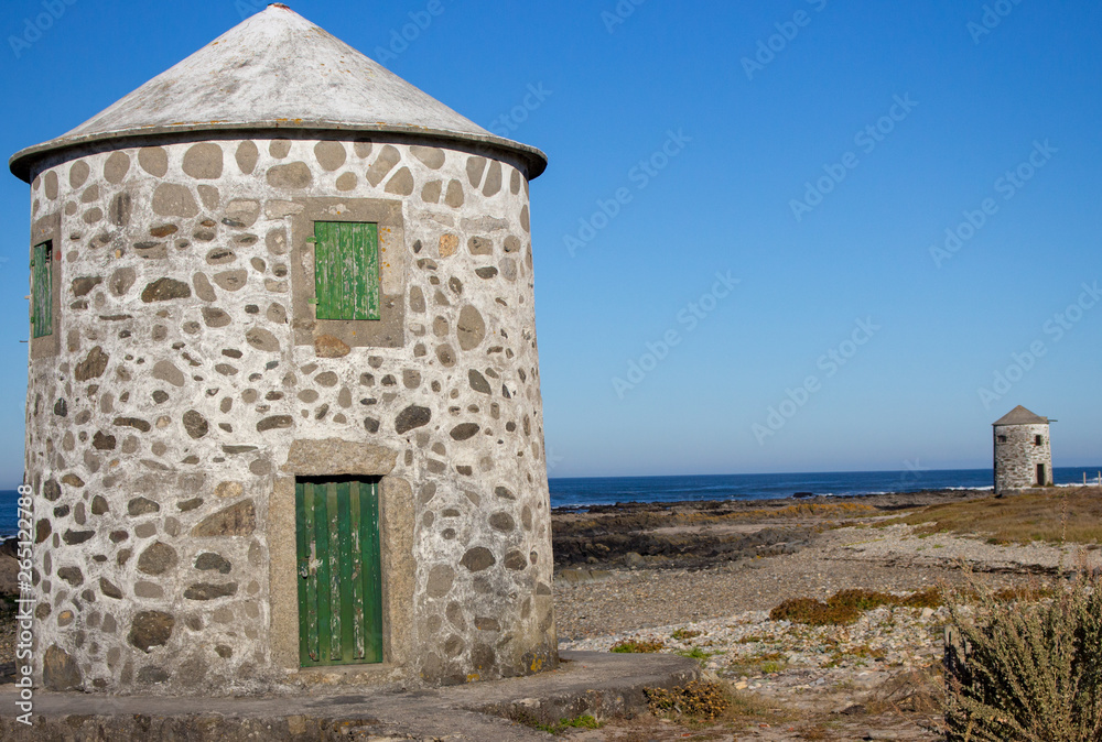 Abandoned old lighthouse with closed green door and windows on Atlantic ocean coast, Portugal. Lighthouse behind wooden fence. Medieval architecture. Landscape on Camino de Santiago. 